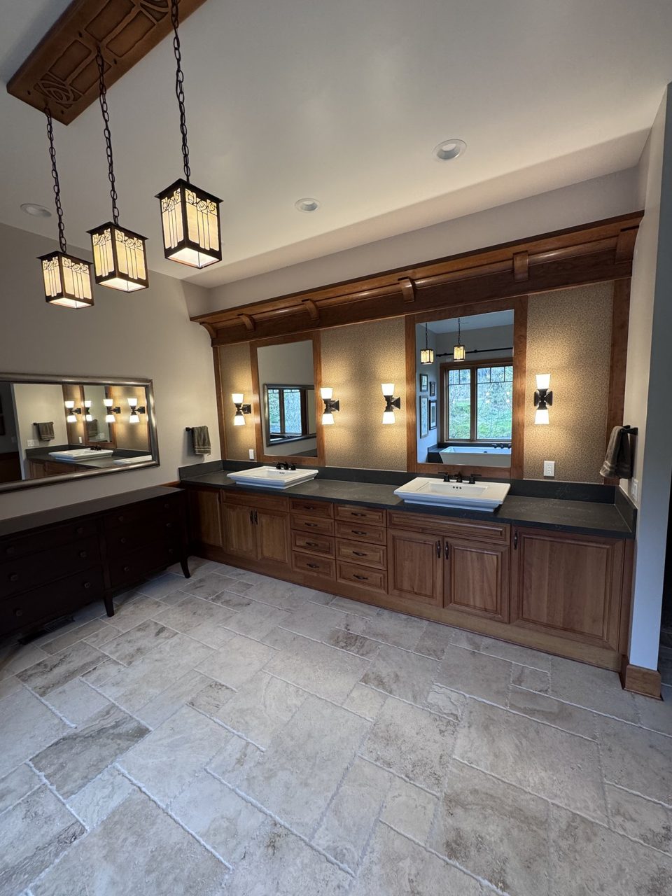 Custom dark wood bathroom vanity with stone counters and framed mirrors