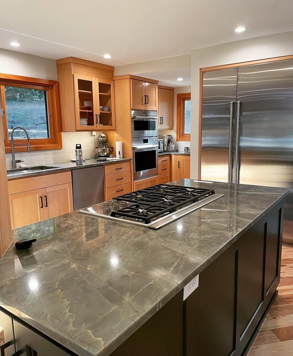 Remodeled kitchen with a stone island, wood cabinetry, and stainless appliances