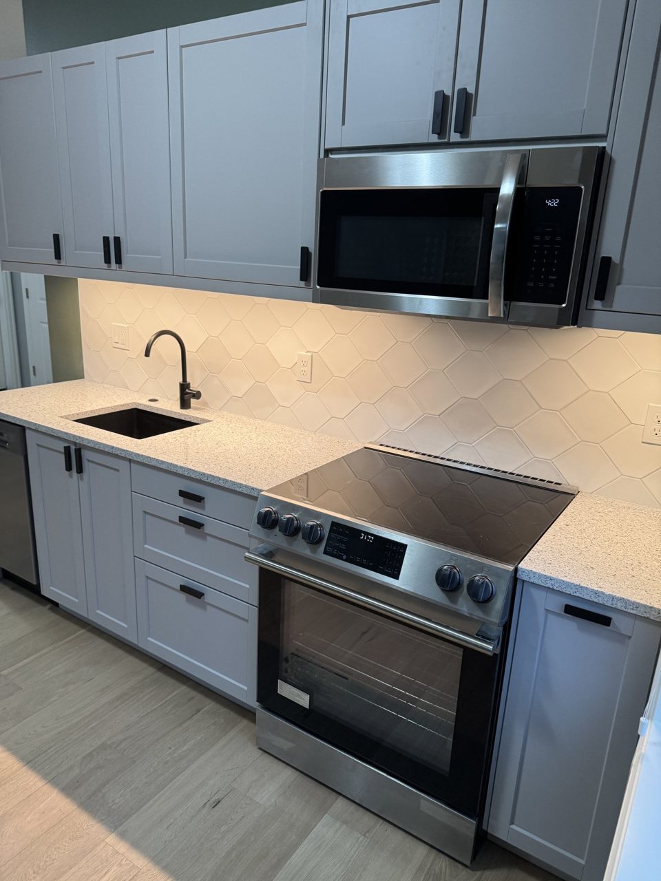 Compact remodeled kitchen with gray cabinets, tile backsplash, and stainless range