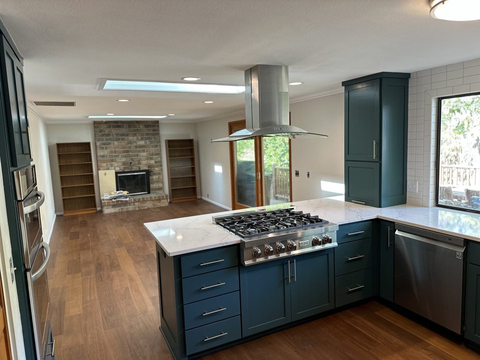 Finished kitchen with forest green cabinets, wood flooring, and a large island