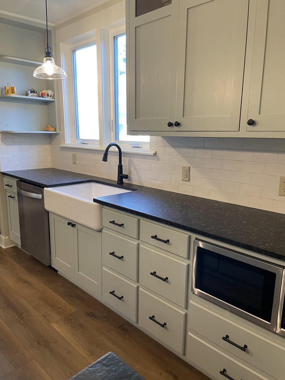 Remodeled kitchen with light cabinetry, dark counters, and wood flooring