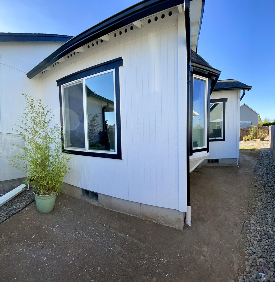 Completed residential addition with white board and batten siding and black window trim