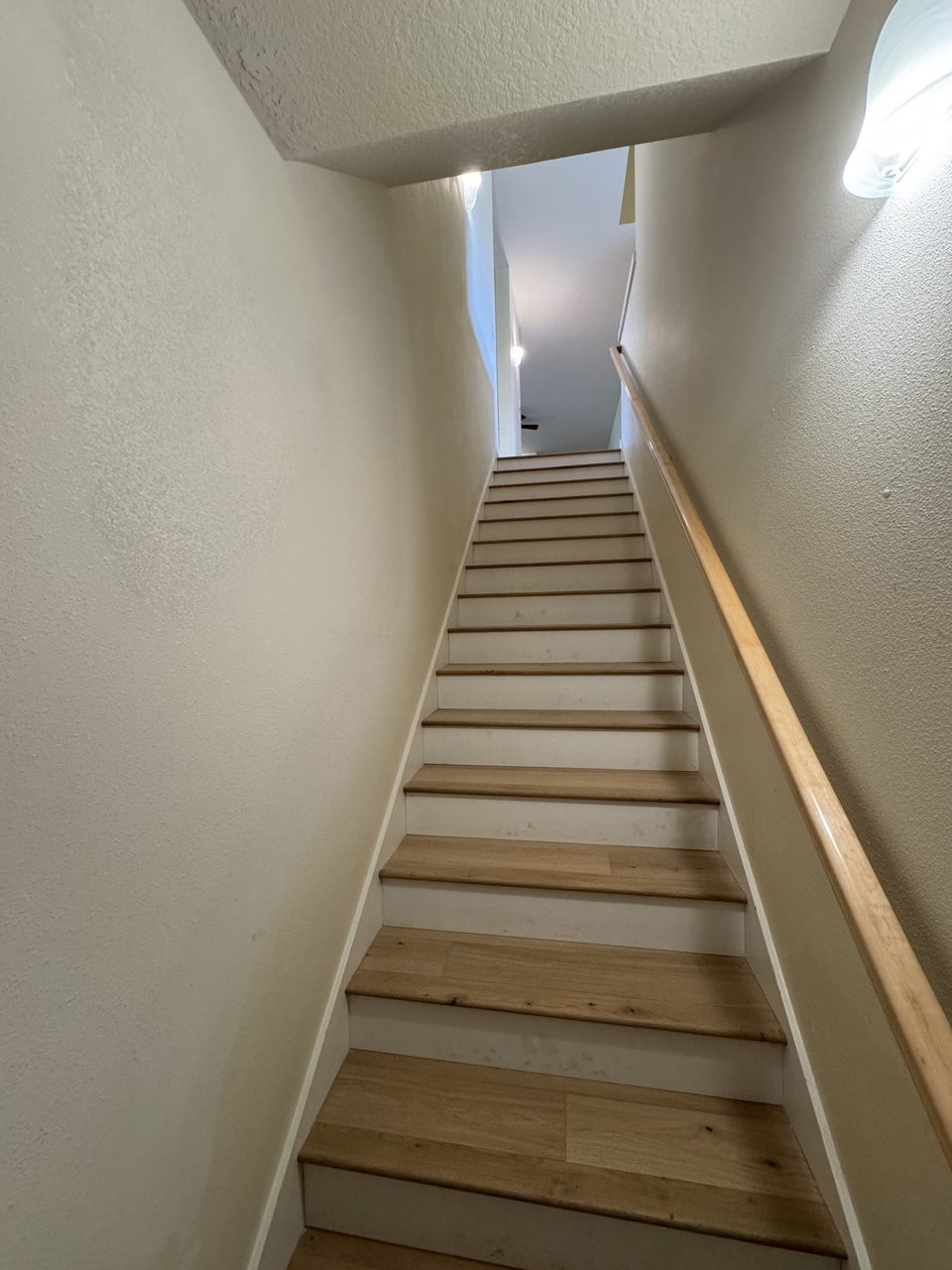 Finished interior staircase with natural wood treads and matching handrail